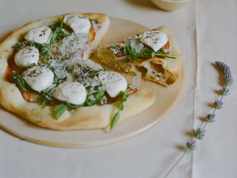Een zuurdesempizza in stukken, met de luchtige korst goed zichtbaar.